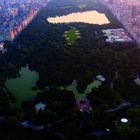 Stadtansicht von oben: Ein großer, grüner Park zwischen dicht bebauten Hochhäusern bei Sonnenaufgang oder -untergang.