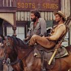 Text: "BOOTS + SHOES". Zwei Männer reiten auf Pferden vor einem Westerngebäude. Einer trägt einen Hut.
