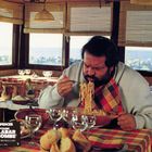 "Bud Spencer, Capitaine Malabar dit ‘La Bombe’, réalisé par Michele Lupo." Ein Mann isst Spaghetti in einem sonnigen Raum.
