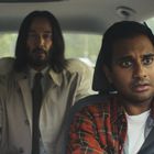 Zwei Männer im Auto: Der Fahrer mit ernstem Gesichtsausdruck, trägt kariertes Hemd. Der Passagier mit Mantel im Hintergrund.