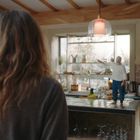 Eine Küche mit einer Person am Küchentresen, eine andere steht davor. Modernes Design, viel natürliches Licht.