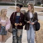 Drei junge Frauen gehen nebeneinander auf einem Gehweg. Sie tragen modisch unterschiedliche Outfits.