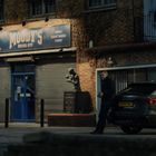 "MOODY'S BOXING GYM" Schild; Boxhalle mit Statue im Hintergrund; Mann steht neben grauem Auto auf der Straße.