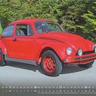 Oktober 2027 Kalender. Ein roter, klassischer VW Käfer parkt auf einer Straße, umgeben von grünen Bäumen und Hügeln.