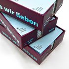 "was wir lieben" in hellem Blau auf violetten Buchboxen, Textbaustein "verlag hermann schmidt", Jahr "2027".