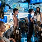 Im Inneren eines technischen Kontrollraums, vier Personen, Monitore mit Weltkarten, intensive Besprechung.