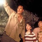 Ein Mann hält eine Laterne hoch in einer Höhle, drei Personen schauen gespannt auf ihn.