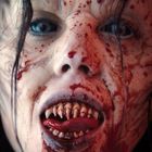 Eine erschreckende Kreatur mit blutverschmiertem Gesicht, spitzen Zähnen und weit geöffneten Augen.