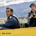 Text: "RIVER: ROB RYDER". Zwei Personen in einem Boot, eine hält eine Kamera. Hintergrund: Berge und bewölkter Himmel.