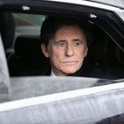 Ein Mann sitzt in einem Auto, schaut aus dem Fenster. Sein Gesicht zeigt einen nachdenklichen Ausdruck.