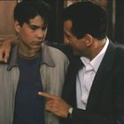 Keine Texte zu sehen. Ein Mann legt dem Jungen den Arm um die Schulter und spricht ernst mit ihm, während er zeigt.