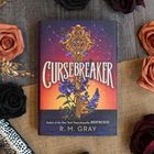 „CURSEBREAKER“, illustriertes Buchcover: Ein goldener Schlüssel, violette Blumen, Sonnenuntergangshimmel. Umgeben von Rosen.