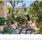 Text: "Villa Frere", Monatszahl "6", "CASARES EDITION". Steinpfade und Pflanzen in einem sonnigen Garten.
