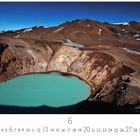 Text: Vulkan Askja, Island. Darunter Kalenderzahlen in zwei Reihen. 

Naturfotografie eines Kratersees in einem Vulkangebiet, umgeben von Bergen unter blauem Himmel.