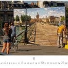 Text: „Pont des Arts“. Mensch malt Brücke, Passanten schauen zu. Es ist eine belebte Straßenszene mit Architektur im Hintergrund.