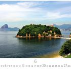 "Niteroi, Rio de Janeiro. Kalender zeigt Juni. Eine üppige grüne Insel im Meer mit Gebäuden, im Hintergrund Berge."