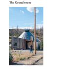 "The Roundhouse." Ein Mann steht vor einem kleinen, runden Gebäude mit Holzelementen in einer kargen Landschaft.