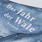 „Das Jahr der Wale. Roman“ in weißen Buchstaben auf blauem Hintergrund, der wie Wasser aussieht.