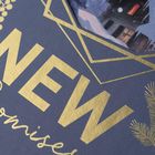 "NEW Promises" in goldener Schrift auf blauem Hintergrund, verziert mit geometrischen Linien, Beeren und Tannenzweigen.