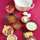 Zutaten arrangiert: Tofu, Linsen, Edamame, Haferflocken, Eier, Käse, Erdnussbutter, Karottenstreifen, Joghurt und ein Topf.