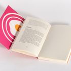 Ein Buch offen aufgeschlagen. Links ein pinkes und orangefarbenes abstraktes Design im Einband, rechts leer.