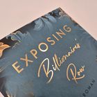 Text: "Exposing Billionaire's Row", "Roman". Dekorative, blumige Illustration in Gold- und Blautönen.