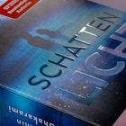 Titel: "SCHATTENLICHT". Oben: "SPIEGEL Bestseller-Autorin". Silhouetten vor blauem Hintergrund.