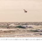 Unten steht: "6", daneben eine Kalendertabelle. Zwei Windsurfer in action auf stürmischer See unter bewölktem Himmel.
