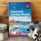 Kapstadt, Garden Route & Winelands. Blaues Cover, Holzuntergrund, Zebra-Figur und Kerze mit Mustern.