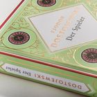 FJODOR DOSTOJEWSKI, Der Spieler. Ein Buch mit grün-rotem Einband, verziert mit Roulette-Motiven.