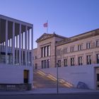 "James-Simon-Galerie" steht an einer modernen Architektur mit Säulen und Treppen, daneben ein klassisches Gebäude.