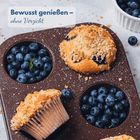 "Bewusst genießen – ohne Verzicht." Zu sehen sind Blaubeeren und Streuselmuffins in einem Backblech.