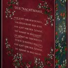 Auf rotem Hintergrund steht: "Der Nachtmahr. Hab acht vor dem Dunkel, vor der Furcht hab acht." Verziert mit Blumen.