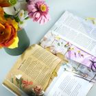 Text auf einer aufgeschlagenen Seite eines Magazins. Daneben ein Blumenstrauß in einer Vase und eine Schere.