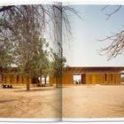 "Place — The Gando Projects — Primary School" steht oben. Ein Schulgebäude aus Holz steht unter Bäumen in einer trockenen Landschaft.