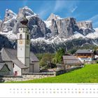 "juni" Kalenderseite mit Dorfkirche vor imposanten, schneebedeckten Bergen und einem klaren, blauen Himmel.