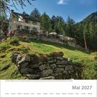 Kalendermonat Mai 2027. Berghütte mit italienischer Flagge in den Alpen, umgeben von Bäumen und Wanderern auf grünem Hang.