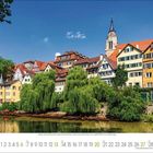 Kalenderseite Juni; Altstadt am Fluss, bunte Fachwerkhäuser, Bäume, blaues Fenster, Kirchturm, Boote im Wasser.