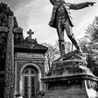 "Familles Desprat et Breissan." Eine Statue eines Mannes mit erhobenem Arm vor einem monumentalen Grabmal. Ziffernreihe unten.