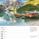 Text: Juni, 21 Sommeranfang Montag, 27 Siebenschläfer Sonntag. Bild: See mit Bergen, Bootshaus und Ruderbooten.