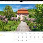 Juni. Barockes Gartenhaus im Kocher­tal, umgeben von Blumen. Ein gepflasterter Weg führt durch einen bunten Garten.