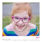 Text: "Juni" in pinker Schrift, mit Kalender darunter.  
Ein lachendes Kind mit lilafarbener Brille trägt einen bunten Pullover.