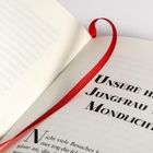 Der Text "UNSERE HEILIGE JUNGFRAU VOM MONDLICHT" steht in einem offenen Buch mit einem roten Leseband.