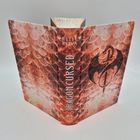 "DRAGON CURSED", Autor: Elise Kova. Der Einband zeigt ein rot-schuppiges Muster mit einem Drachenemblem.