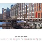 Kalender: Juni. Szene einer belebten Uferpromenade mit Cafés und eleganten Gebäuden im Hintergrund.