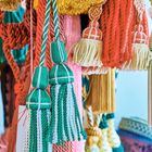 Verschiedene Quasten in bunten Farben wie Grün, Rot, Gelb und Blau hängen dicht beieinander.