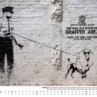 Text: "THIS WALL IS A DESIGNATED GRAFFITI AREA." Darstellung eines Polizisten mit Hund an einer Wand. Kalender mit Januar-Daten.