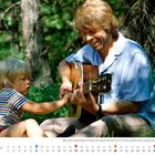 Juni. Björn mit Sohn Christian beim Midsommar-Fest 1982 in Schweden. Sie sitzen im Grünen, Björn spielt Gitarre.