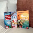 Drei Kinderbücher auf einem Sofa: "Fiete Hering", "Mira und die Maus", "Henry sucht ein Zuhause". Farbenfrohe Illustrationen.