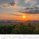 Kalenderblatt für Juni 2027. Sonnenuntergang über grüne Hügel und Wälder.